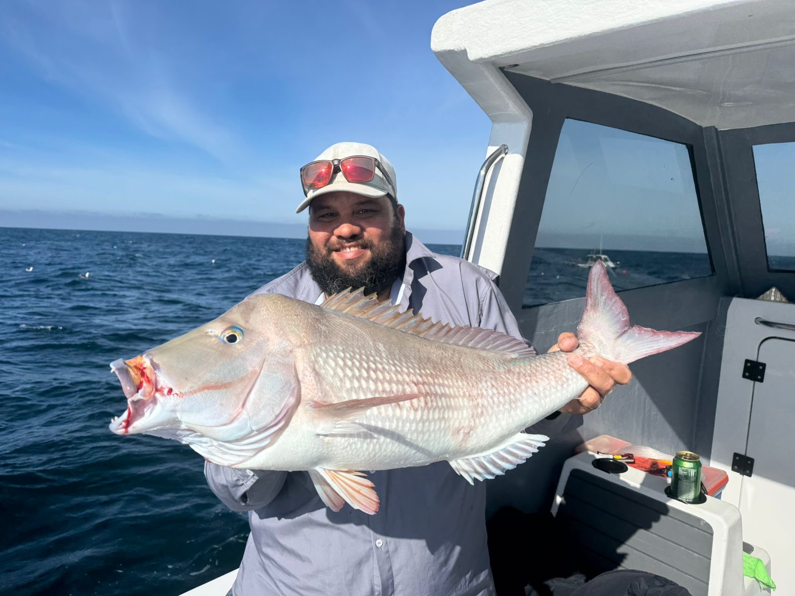 Bearded angler holding a fish beside the cabin of the On Point boat