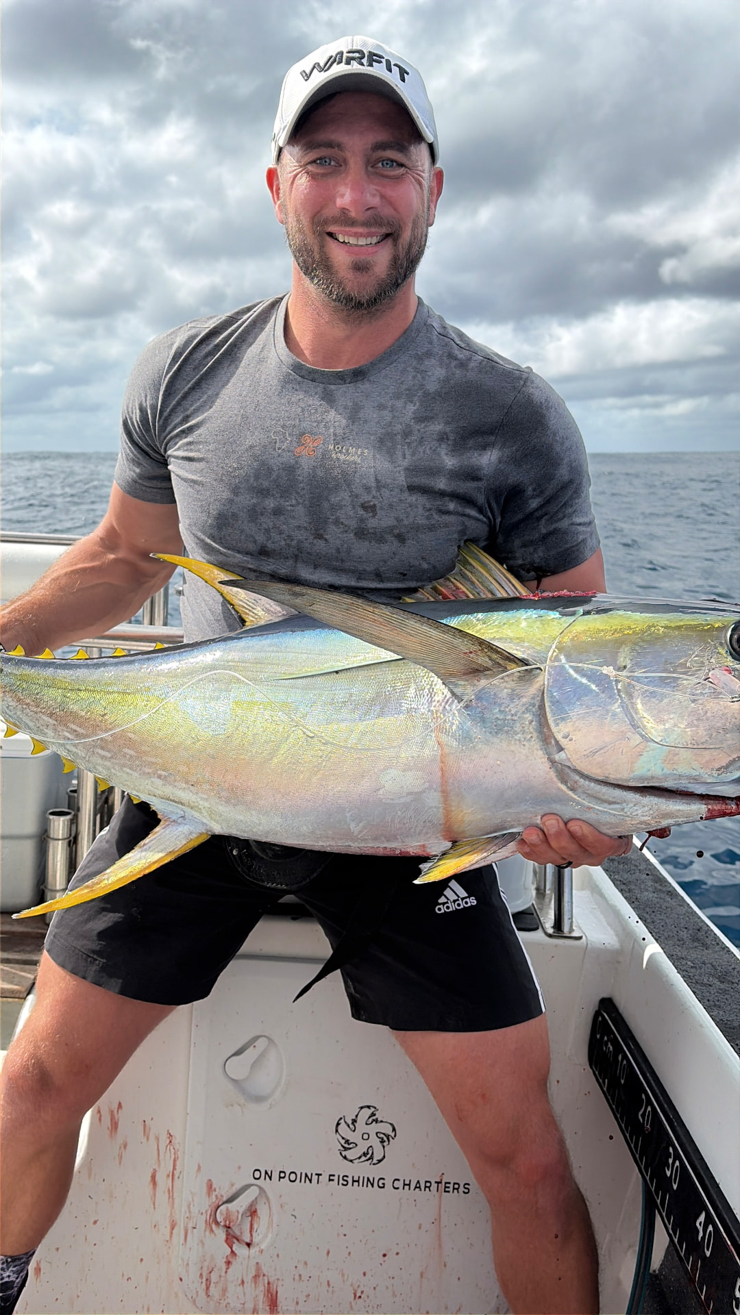 Angler holding a yellowfin tuna on the stern of the On Point boat offshore Port Alfred