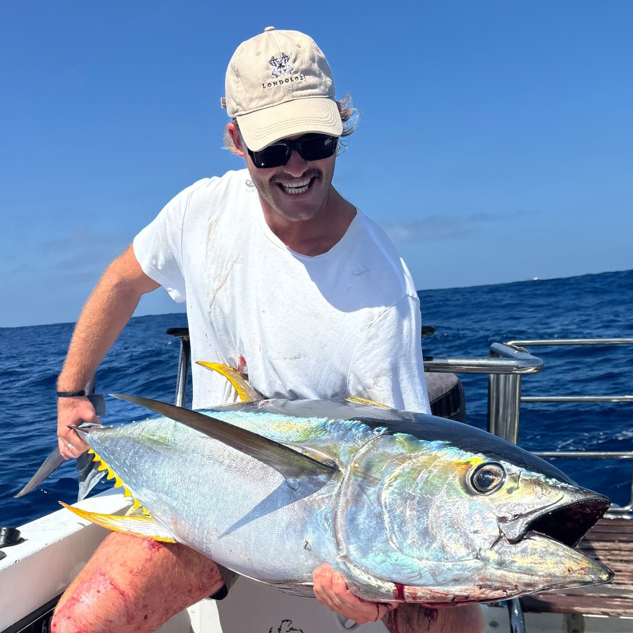 Angler holding a yellowfin tuna across his lap on the deck of the On Point boat offshore Port Alfred