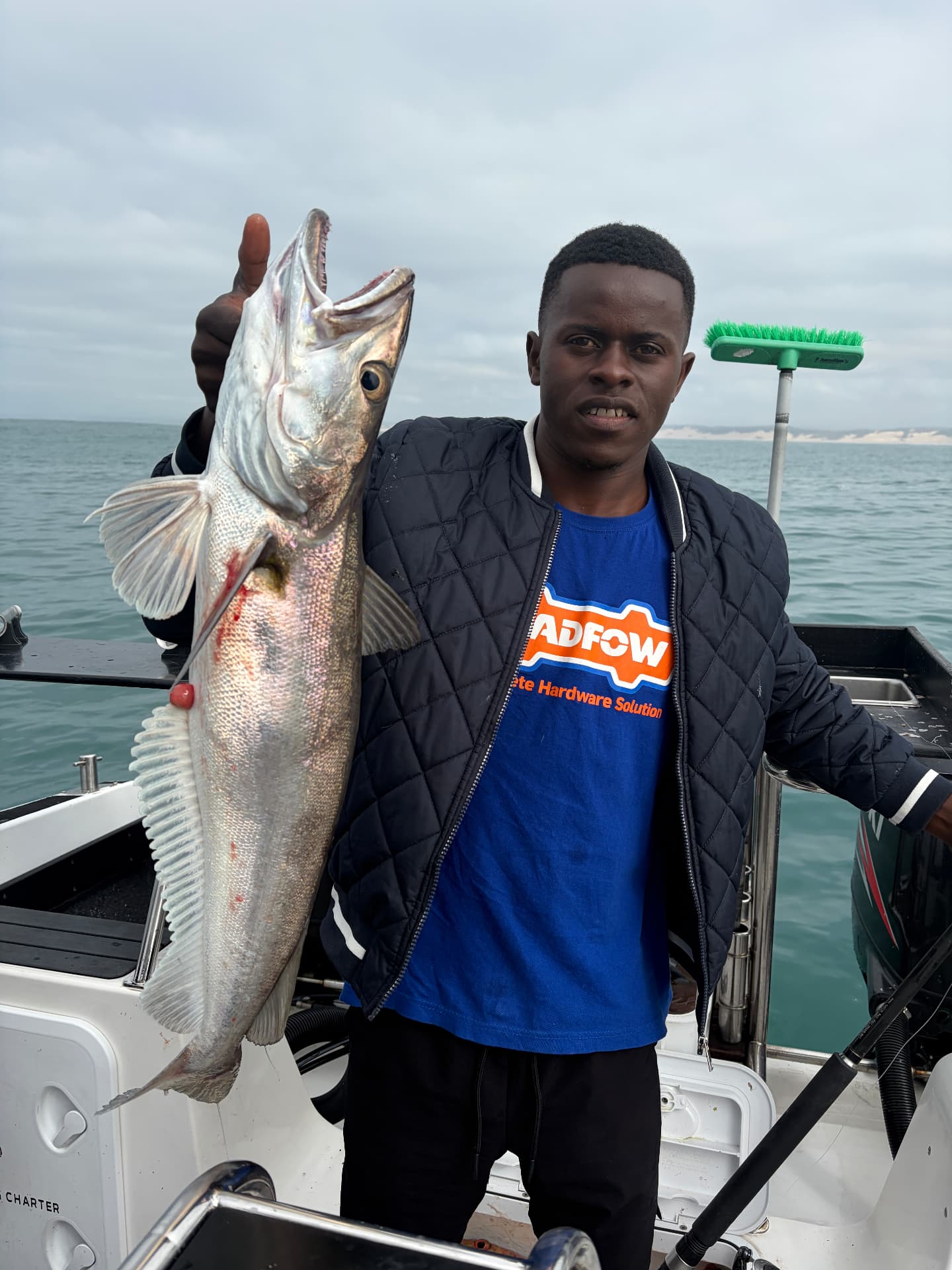 Young angler giving a thumbs-up while holding a fish on the stern of the On Point boat